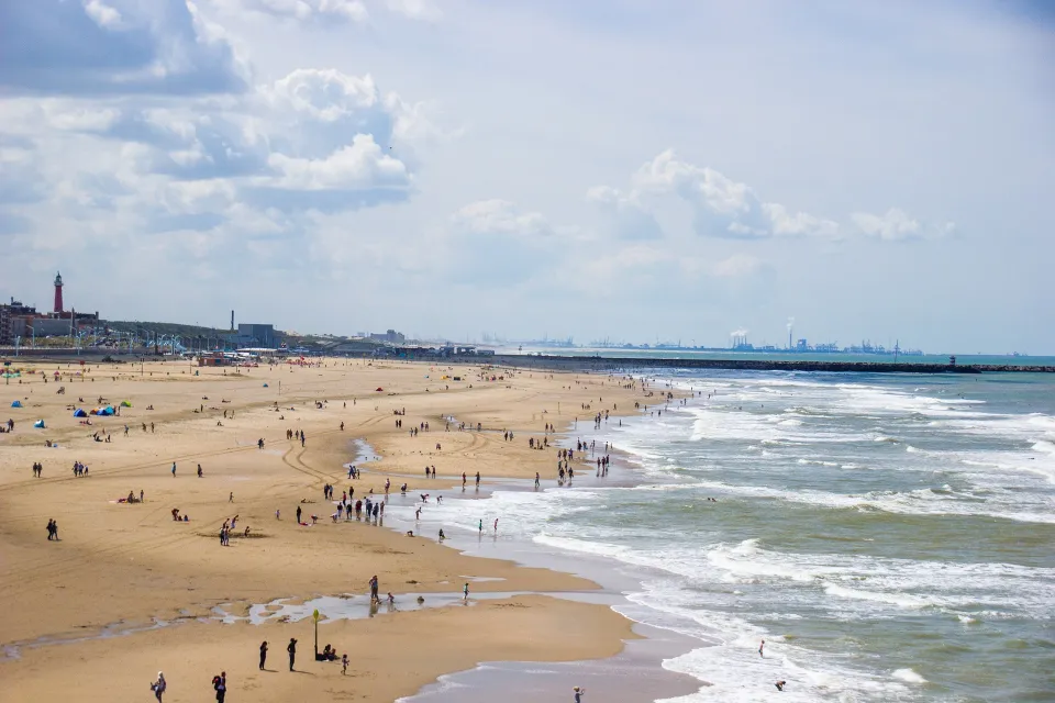 Breed strand met bezoekers en de pier in de verte