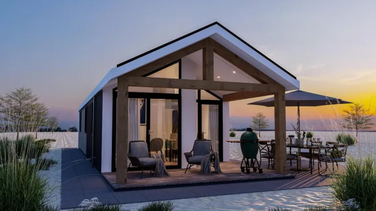 Moderne vakantievilla met glazen puntgevel en terras met eettafel bij zonsondergang