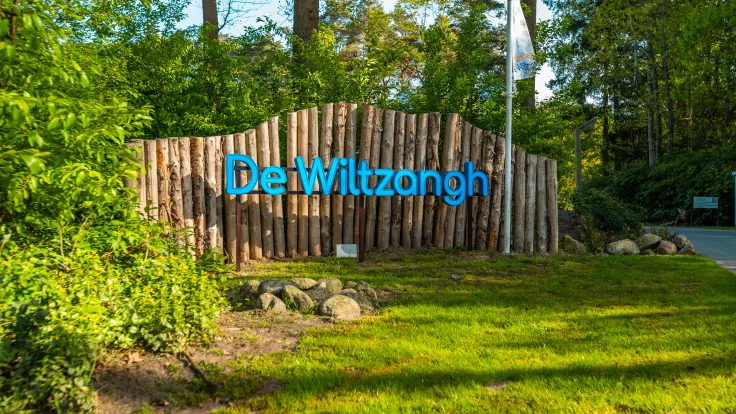 Houten naambord met de naam De Wiltzangh bij de ingang van het park in het groen