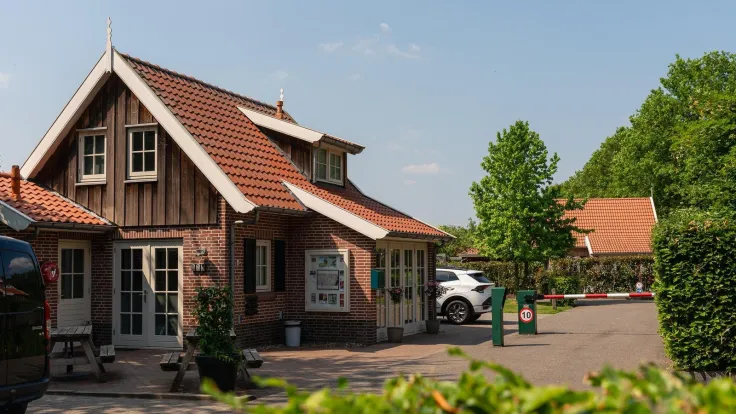 Receptiegebouw met rood pannendak en houten gevel bij de entree van het park