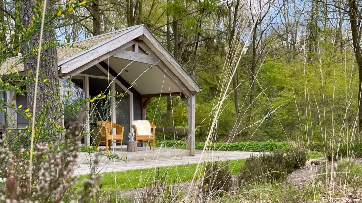 Houten overkapping met bankjes aan een pad tussen de bomen