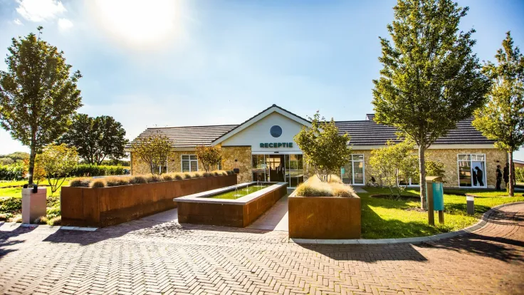 Receptiegebouw met een geplaveid plein en cortenstalen plantenbakken