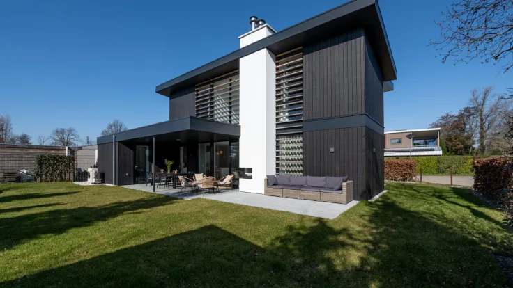 Moderne villa met donkere gevel, wit accent en een grasveld