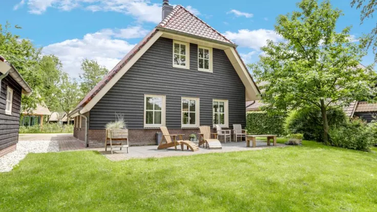 Vakantiewoning met donkere gevel en terras op een groot gazon